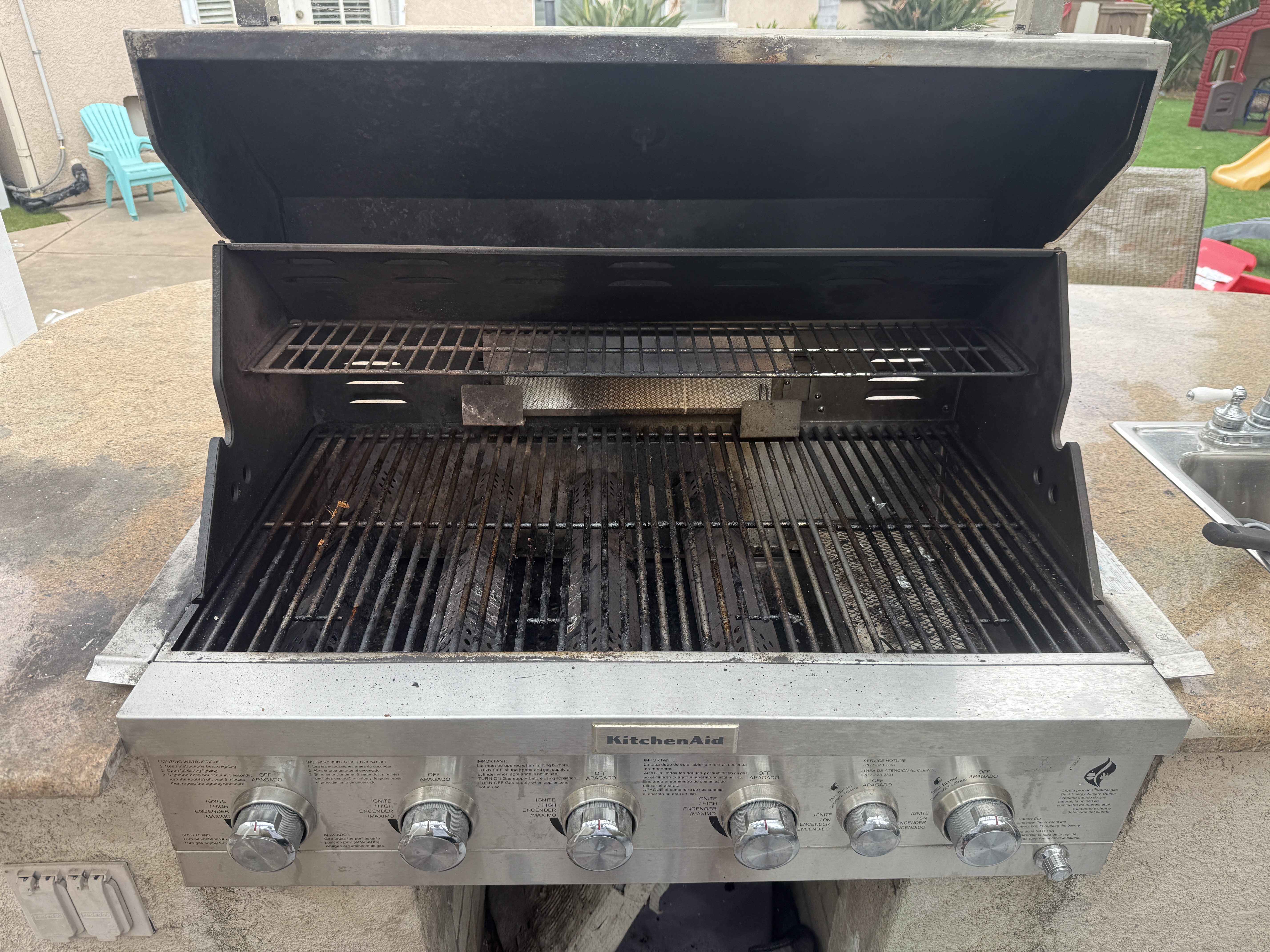 Gas grill with heavy grease buildup before cleaning in San Diego